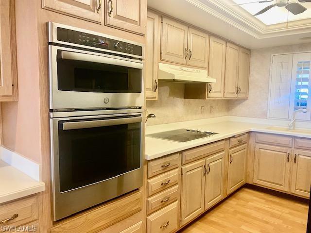 Kitchen with ceiling fan, crown molding, sink, stainless steel double oven, and light hardwood / wood-style flooring