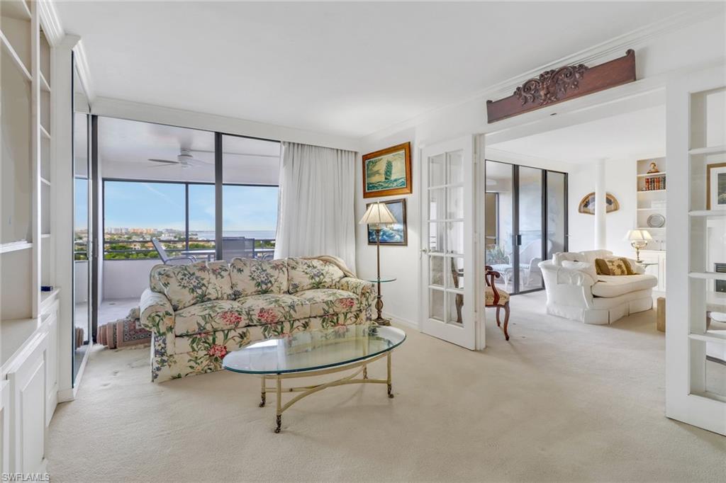 Living room with crown molding, french doors, built in features, ceiling fan, and light carpet