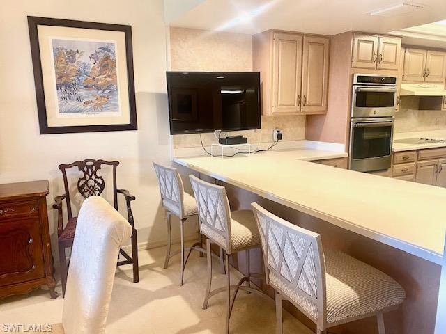 Kitchen with decorative backsplash, stainless steel double oven, built in desk, and a breakfast bar