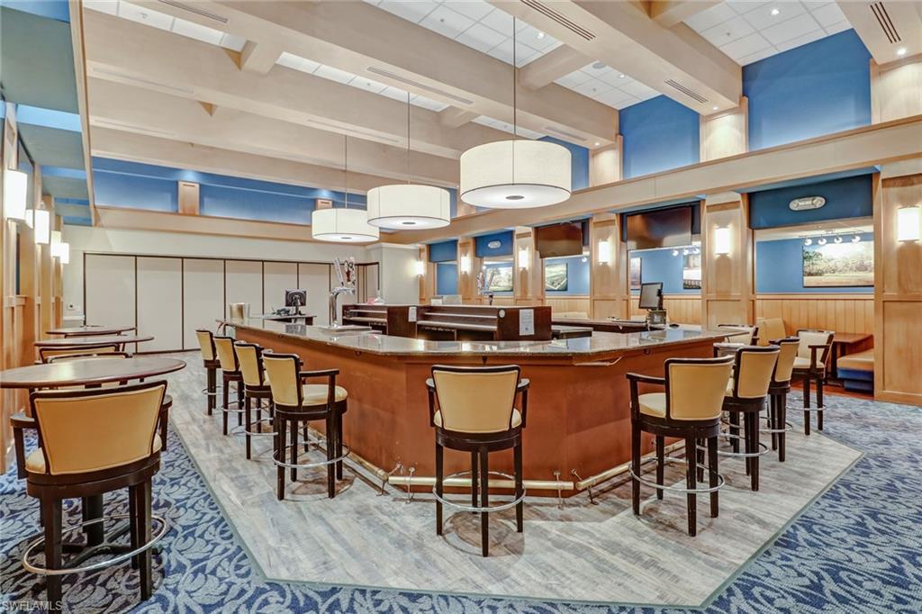 Bar with pendant lighting, beamed ceiling, and a towering ceiling