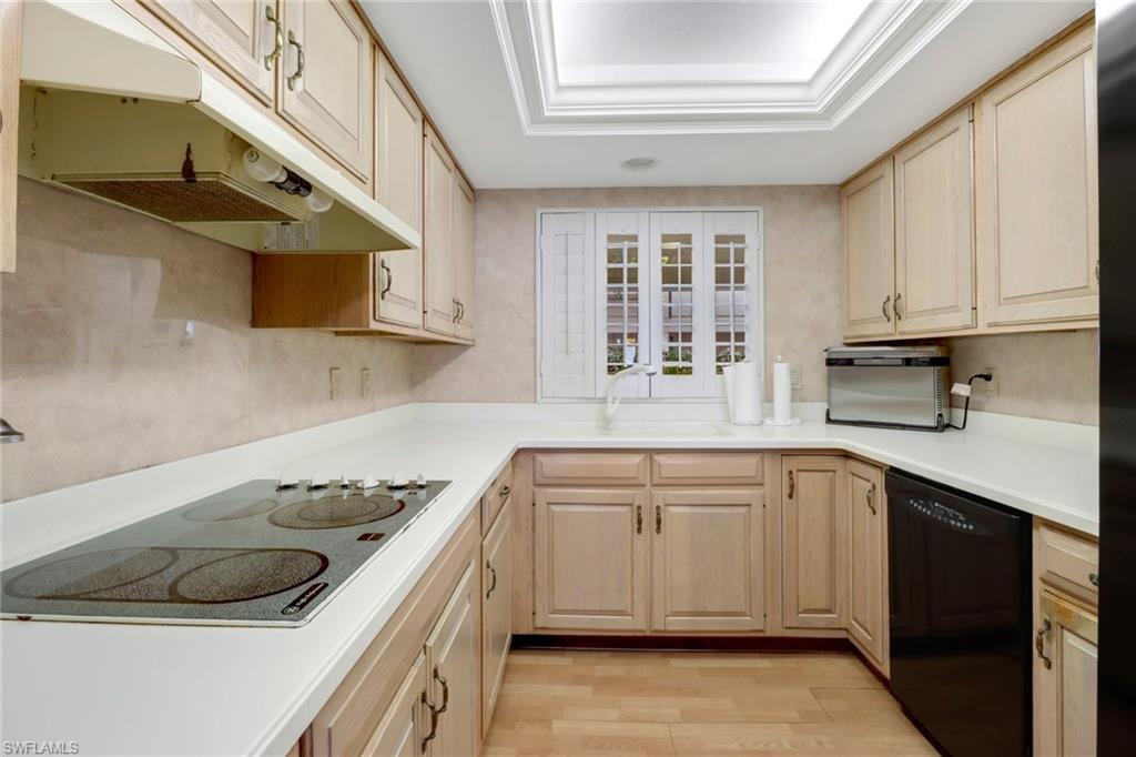 Kitchen featuring electric stovetop, light brown cabinets, sink, dishwasher, and light hardwood / wood-style flooring