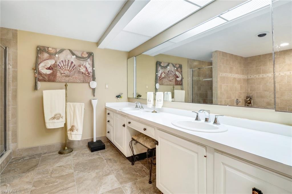 Bathroom featuring dual vanity, walk in shower, and tile patterned floors
