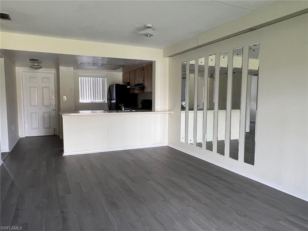 Kitchen with dark wood-type flooring, freestanding refrigerator, and under cabinet range hood