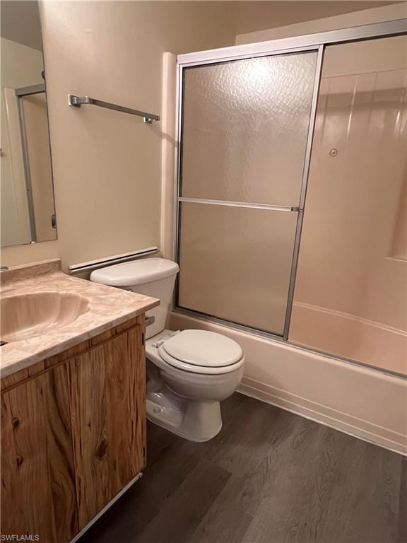 Full bath featuring vanity, enclosed tub / shower combo, and wood finished floors