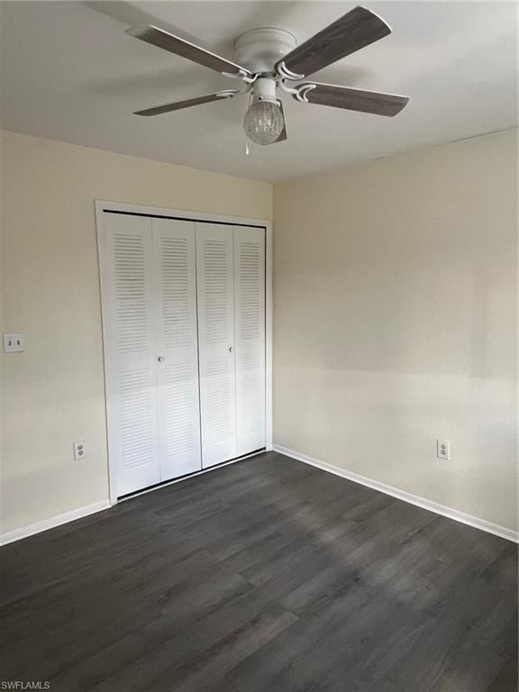 Unfurnished bedroom featuring dark wood-style floors, a closet, and a ceiling fan