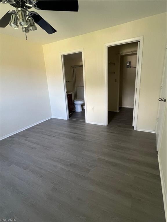 Unfurnished bedroom with dark wood-style flooring, ensuite bathroom, and ceiling fan
