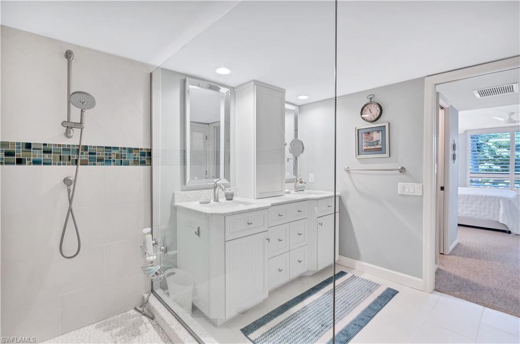 Recently redone Primary bathroom featuring a tile shower, double vanity, connected bathroom, recessed lighting, and tile patterned floors