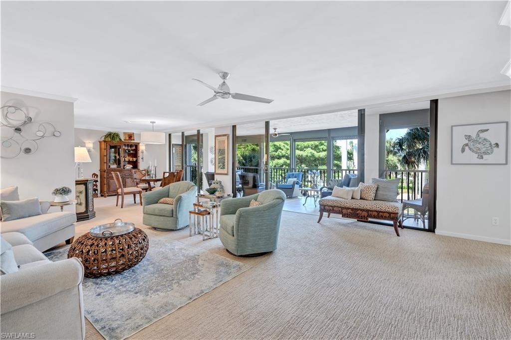 Living area featuring ceiling fan, light carpet, floor to ceiling windows, and ornamental molding