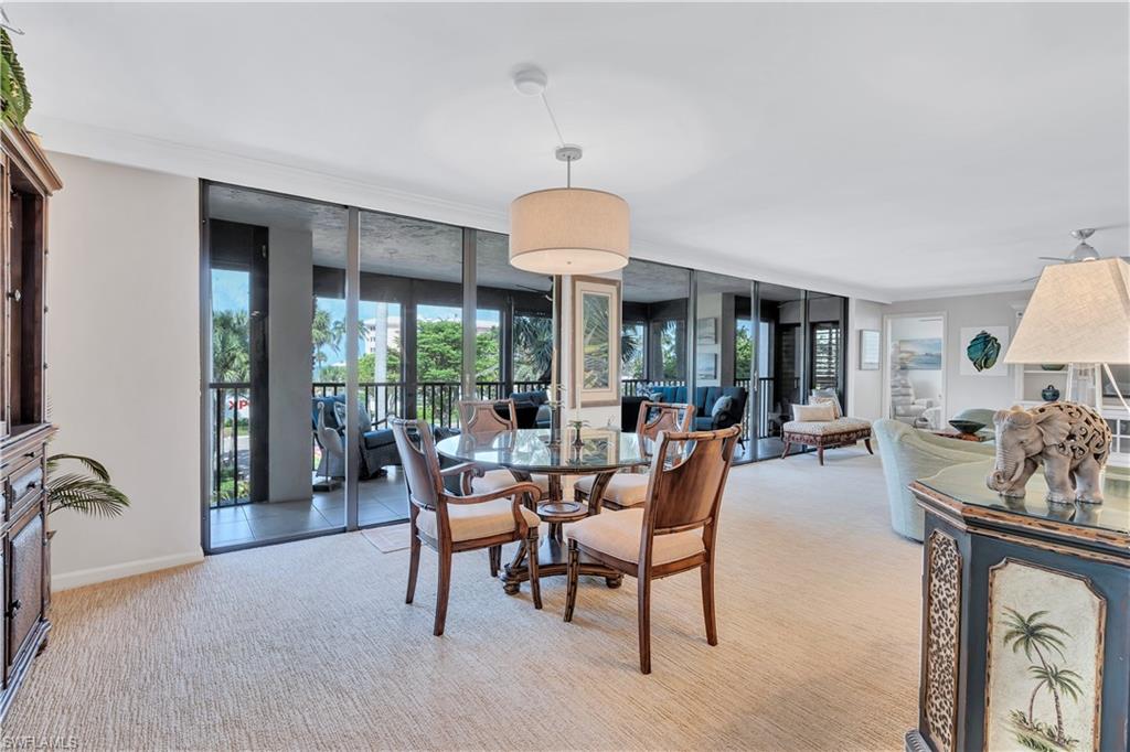 Dining space with expansive windows, light carpet, and crown molding