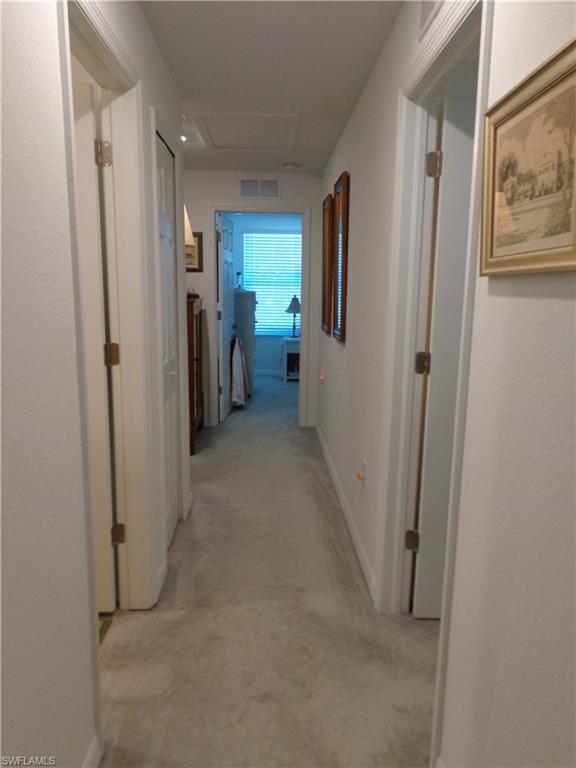 Corridor featuring baseboards and light carpet