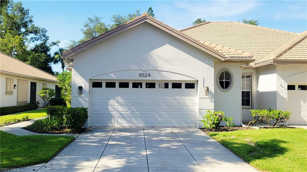 View of front facade featuring an attached garage, stucco siding, driveway, and a front lawn