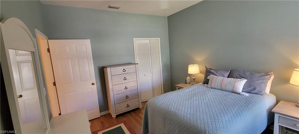 Bedroom with wood finished floors and a closet