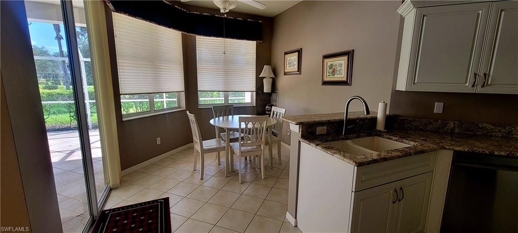 Kitchen with countertops, light tile patterned flooring, dishwasher, a ceiling fan, and white cabinetry