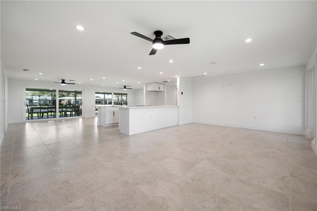 Open living area with tile floors, modern finishes, and sliding glass doors to the lanai and water views.