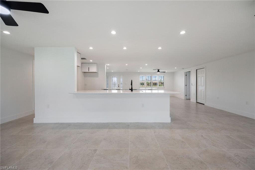 Kitchen with a ceiling fan, recessed lighting, white cabinets, a peninsula, and light stone countertops