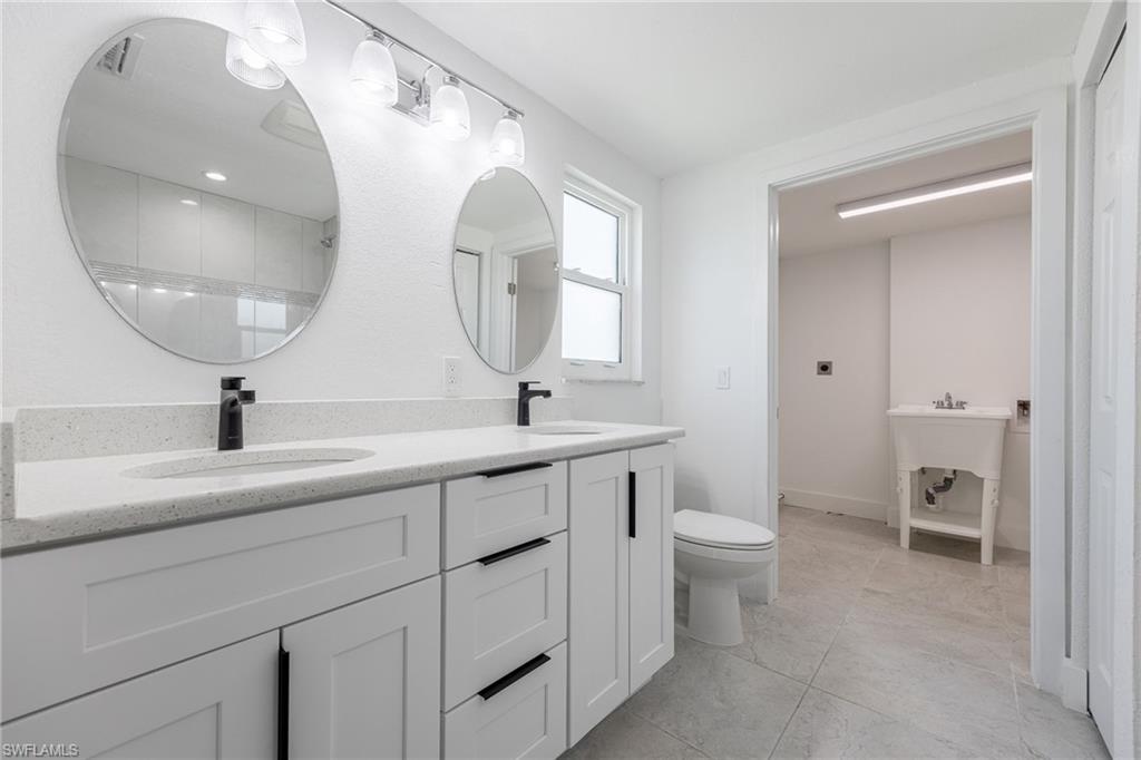 Master Bathroom featuring double vanity, walk-in shower and access to laundry area