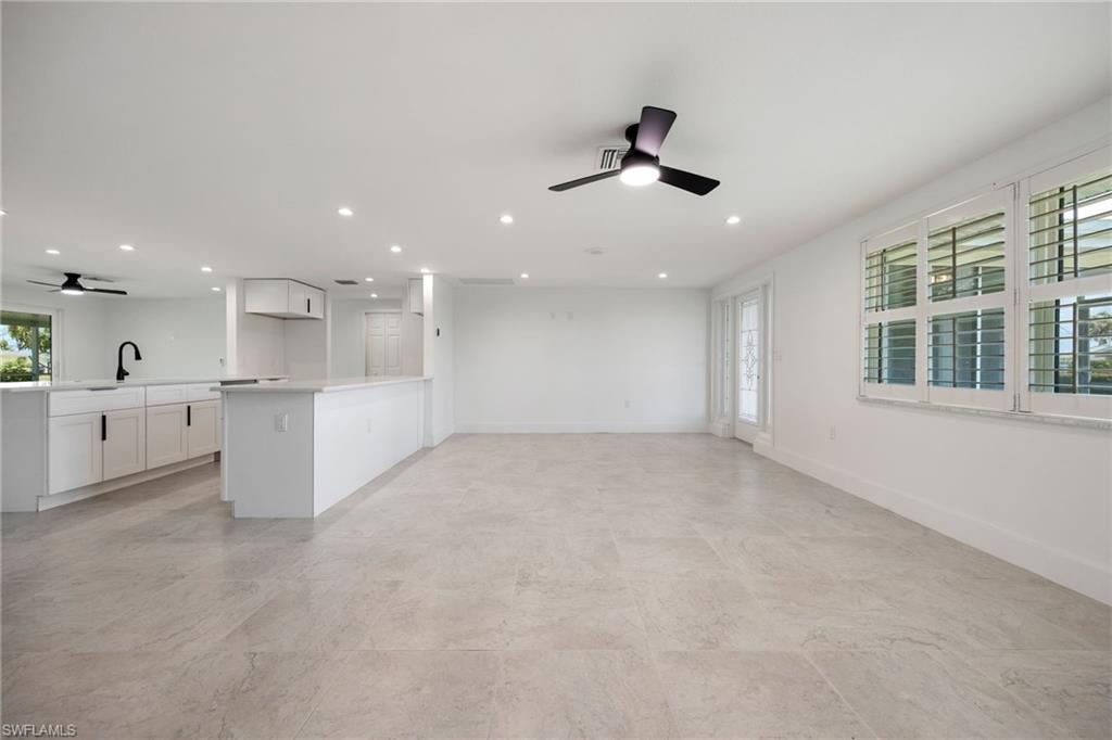 Bright open living space with tile floors, plantation shutters, and direct flow to the kitchen