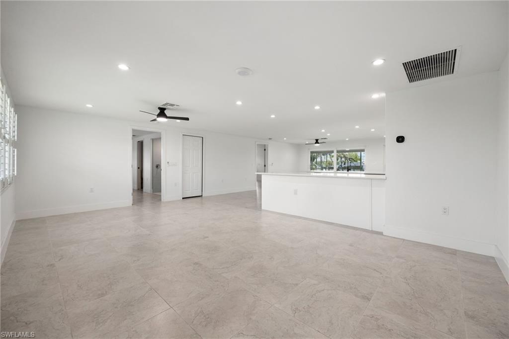 Spacious open-concept living room as you step in from the front door, featuring neutral tile flooring, recessed lighting, and a seamless flow into the kitchen and dining areas.