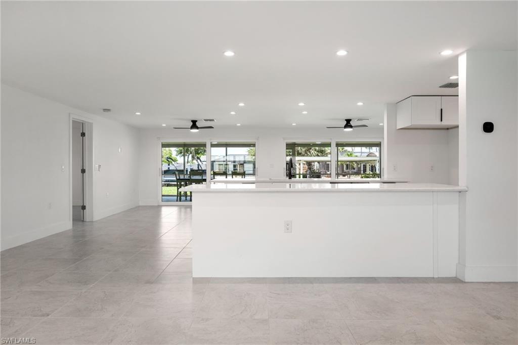 Modern kitchen with a large peninsula, open sightlines to the living area, and sliding glass doors showcasing waterfront views.