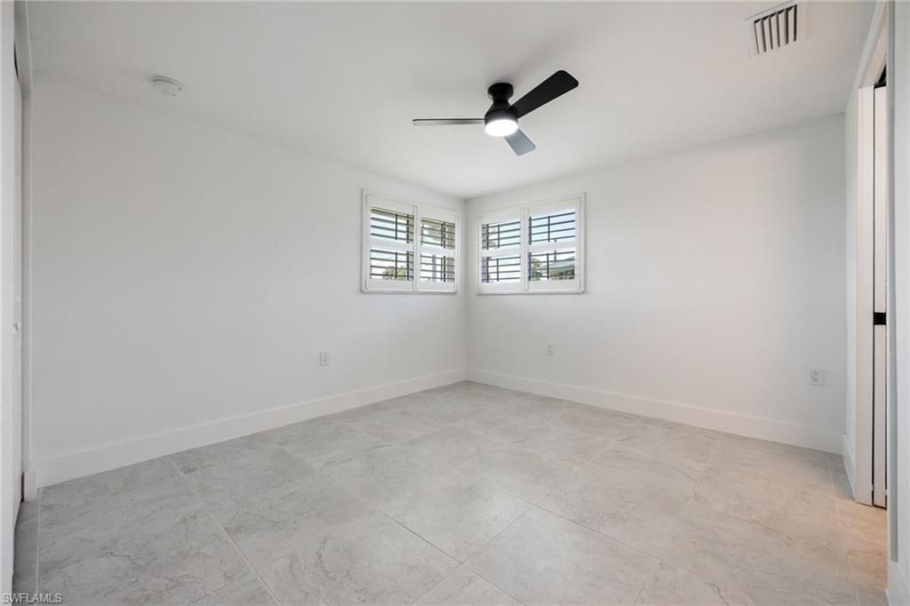 Guest bedroom with ensuite full bath, tile flooring, plantation shutters, and ceiling fan