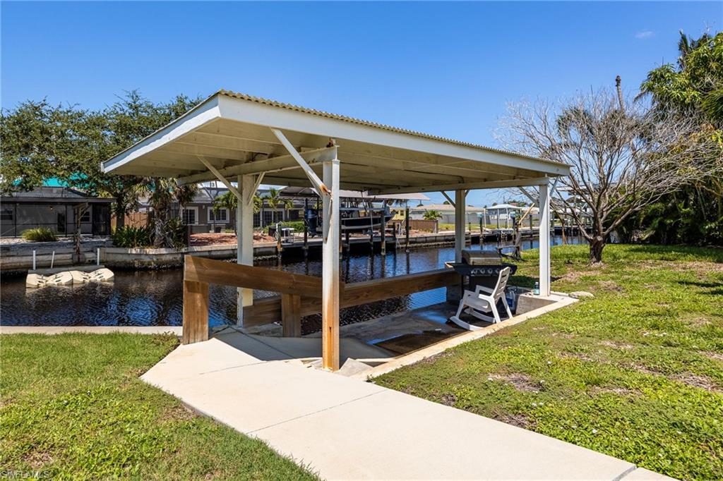 Covered boat house with concrete seawall, lawn area, and serene canal views.