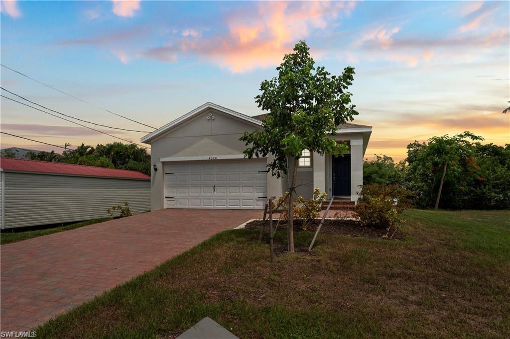 View of front facade featuring decorative driveway, an attached garage, stucco siding, and a yard