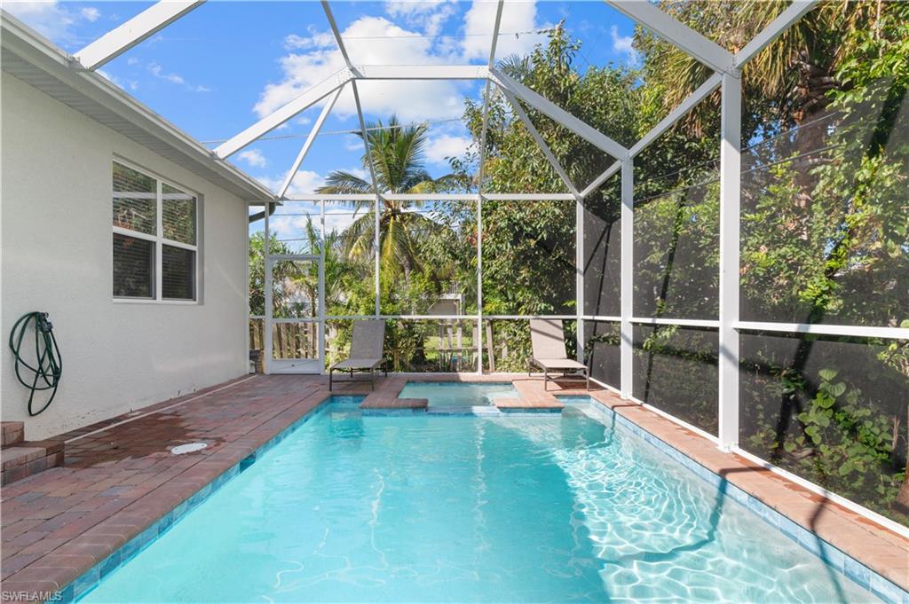Outdoor pool featuring an in-ground hot tub, glass enclosure, and a patio