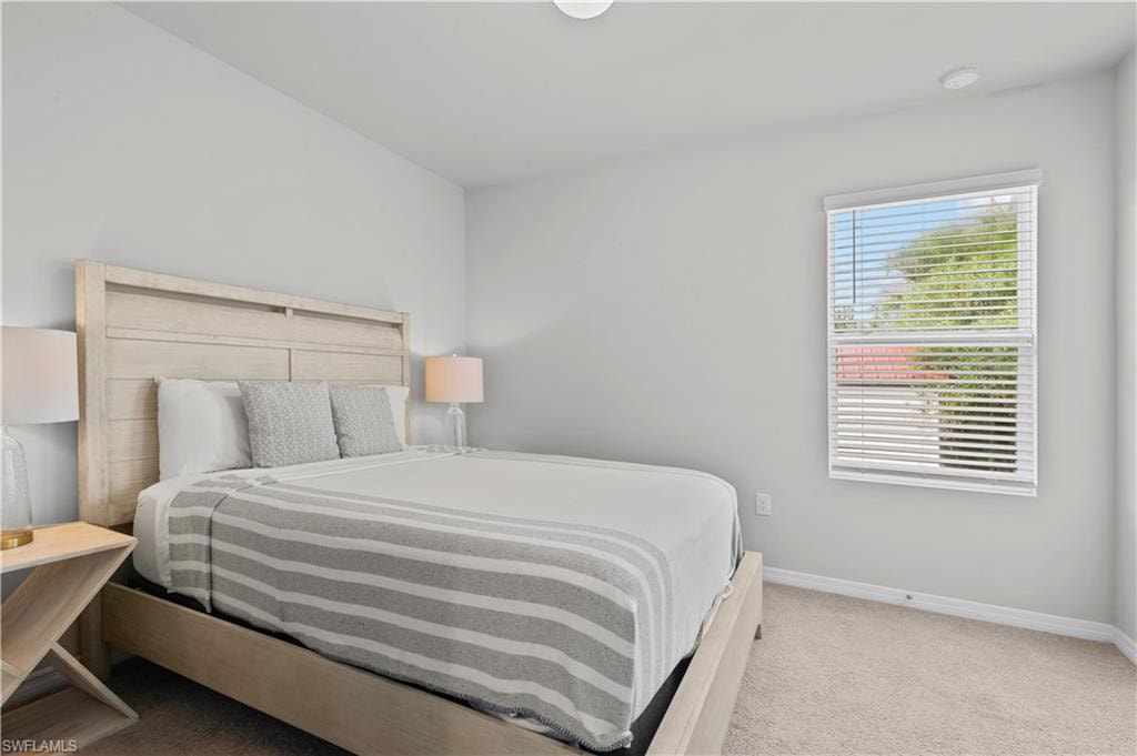 Bedroom featuring light carpet and baseboards