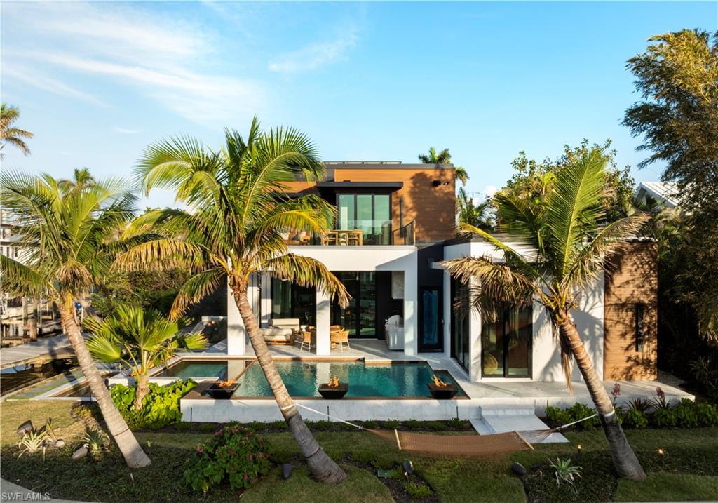 Rear view of property with a swimming pool with hot tub, a balcony, and a patio