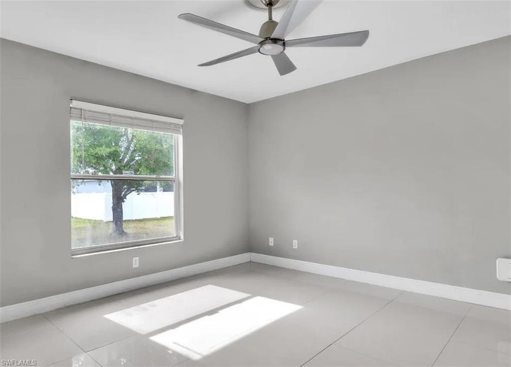 Empty room featuring a ceiling fan and light tile patterned flooring
