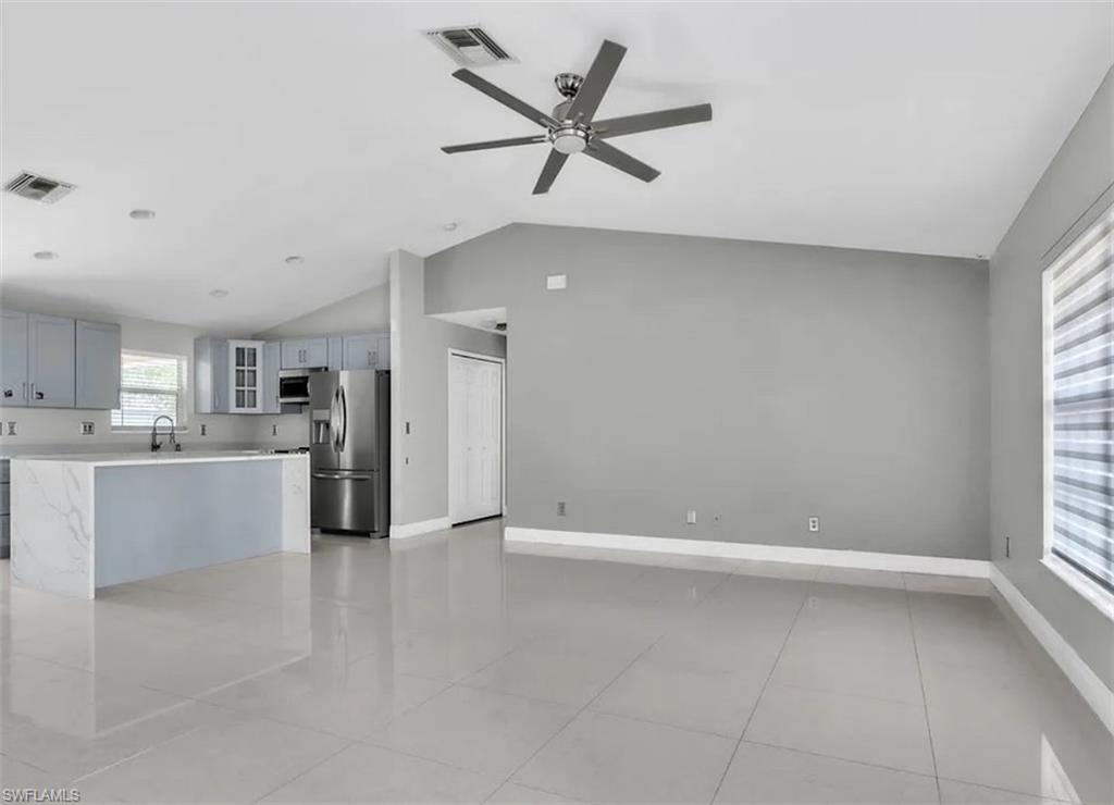Unfurnished living room with lofted ceiling, a ceiling fan, and light tile patterned floors