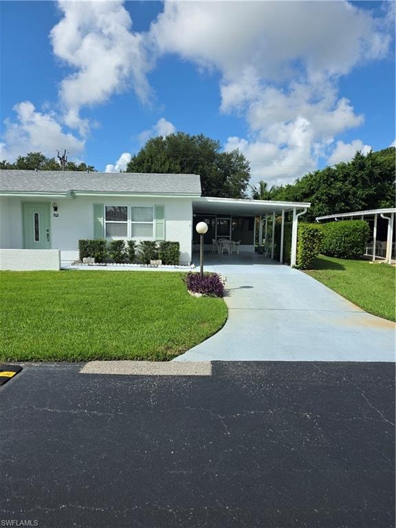View of front of home featuring an attached carport, driveway, a front yard, and stucco siding