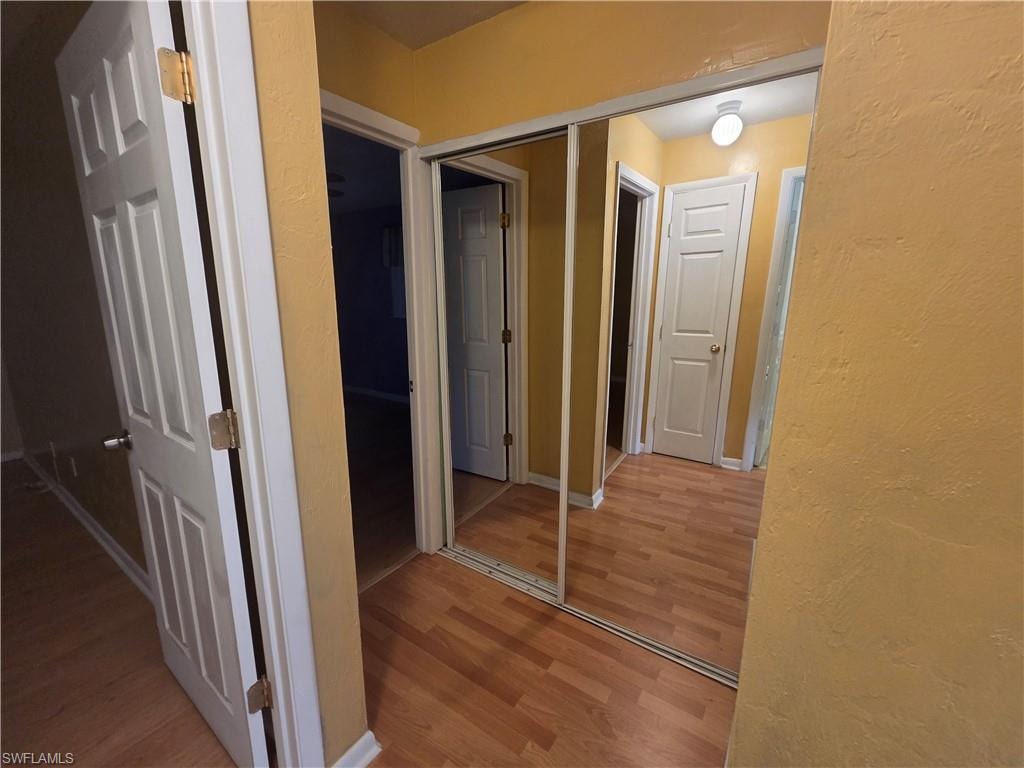 Hallway featuring wood finished floors and a textured wall
