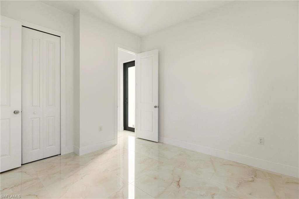Unfurnished bedroom with light marble finish flooring and a closet