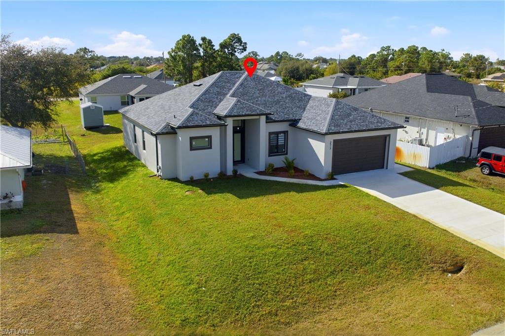 View of front of home featuring stucco siding, roof with shingles, driveway, a garage, and a residential view