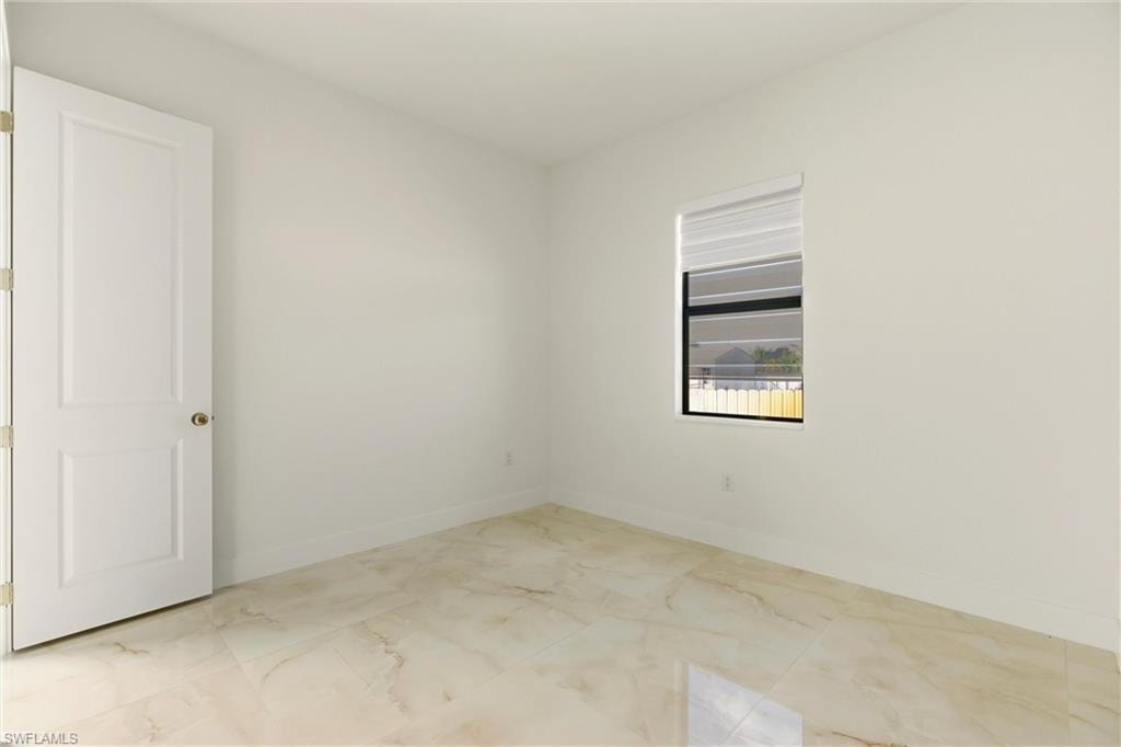Spare room featuring light marble finish flooring and baseboards