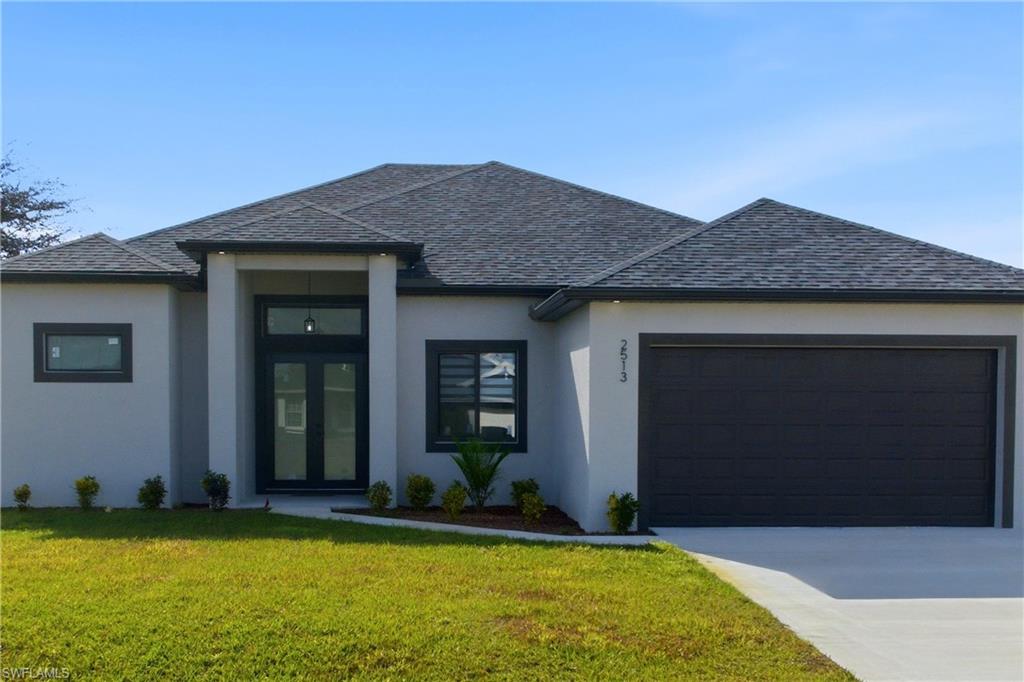 View of front of property with a front yard, stucco siding, driveway, and an attached garage