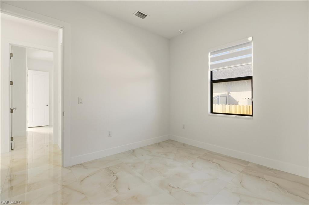 Unfurnished room featuring light marble finish flooring and baseboards