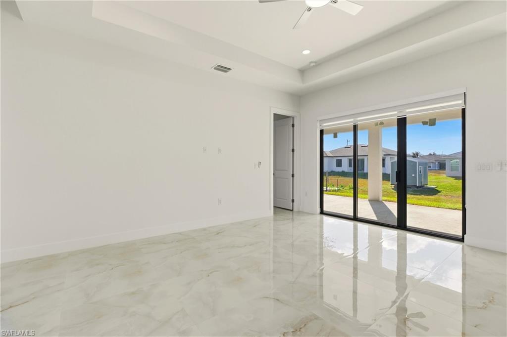 Spare room with light marble finish flooring, a tray ceiling, ceiling fan, recessed lighting, and a residential view