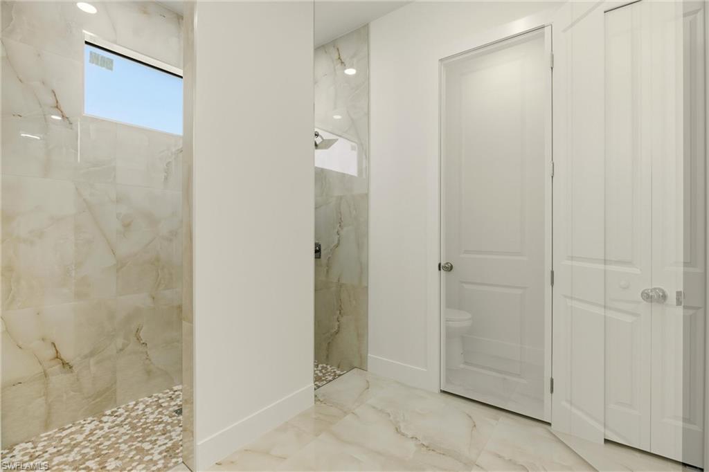 Bathroom featuring a marble finish shower and marble tiled floors