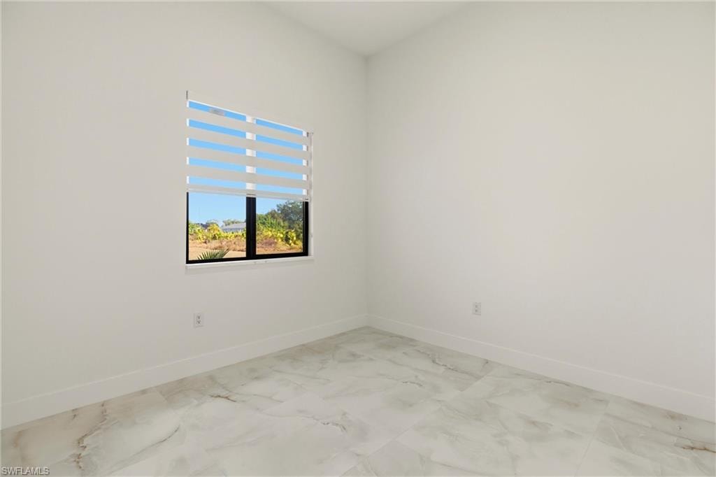 Spare room featuring baseboards and light marble finish floors