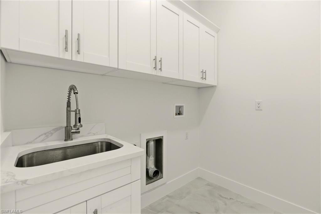 Laundry room featuring light marble finish flooring, cabinet space, and washer hookup