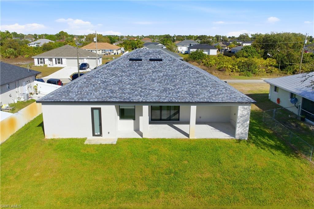 Rear view of property featuring a fenced backyard, a residential view, a patio area, and stucco siding