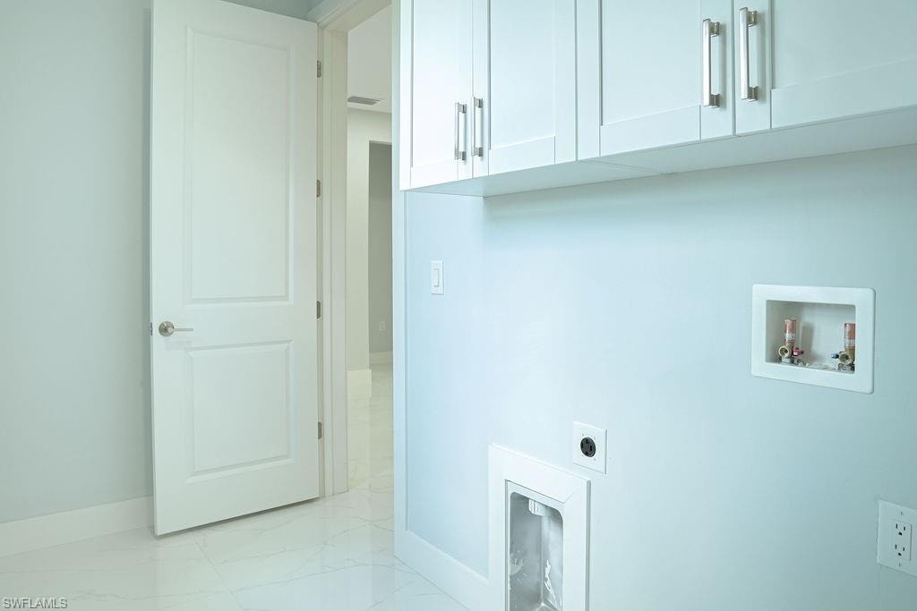 Washroom featuring electric dryer hookup, cabinet space, washer hookup, and light marble finish flooring