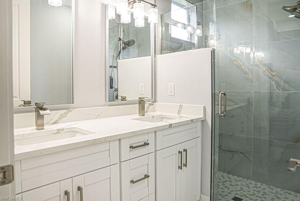 Full bathroom featuring a shower stall and double vanity