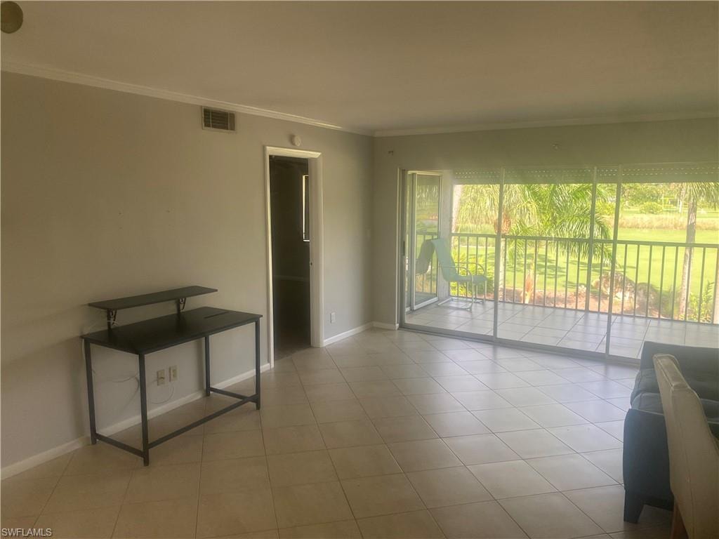 Empty room with ornamental molding and light tile patterned floors