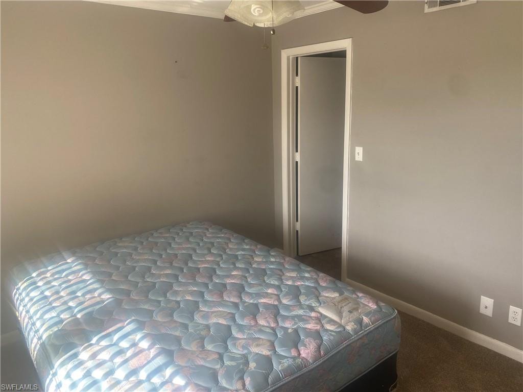 Bedroom with a ceiling fan and dark carpet