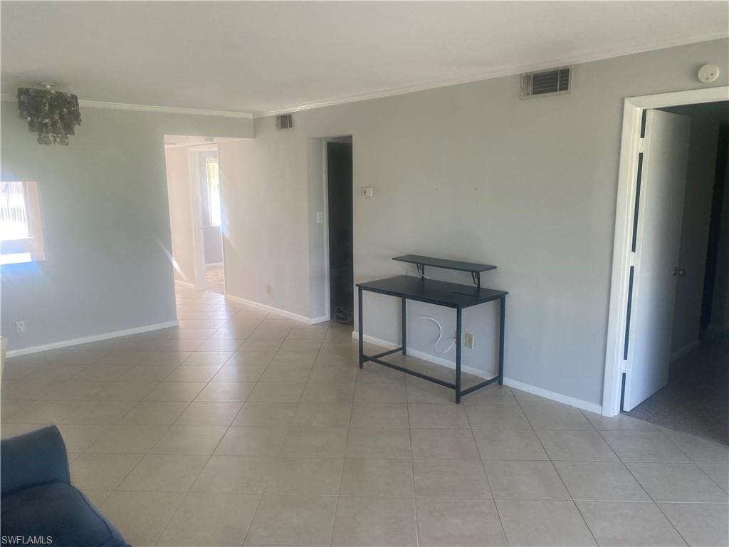 Empty room featuring ornamental molding and light tile patterned floors