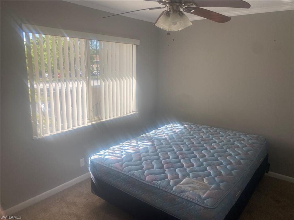 Bedroom featuring dark carpet, crown molding, and ceiling fan