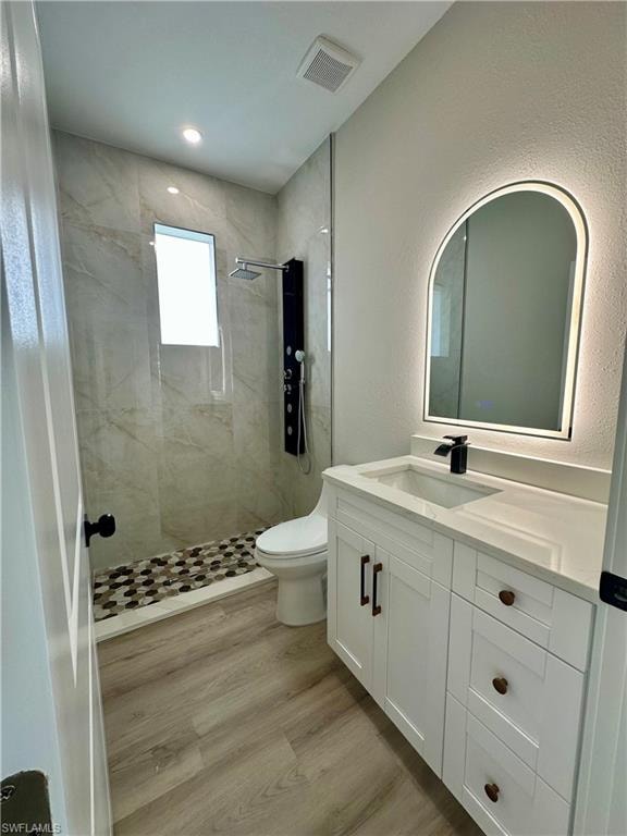 Unfurnished room with a barn door, light wood-style floors, a tray ceiling, recessed lighting, and a ceiling fan